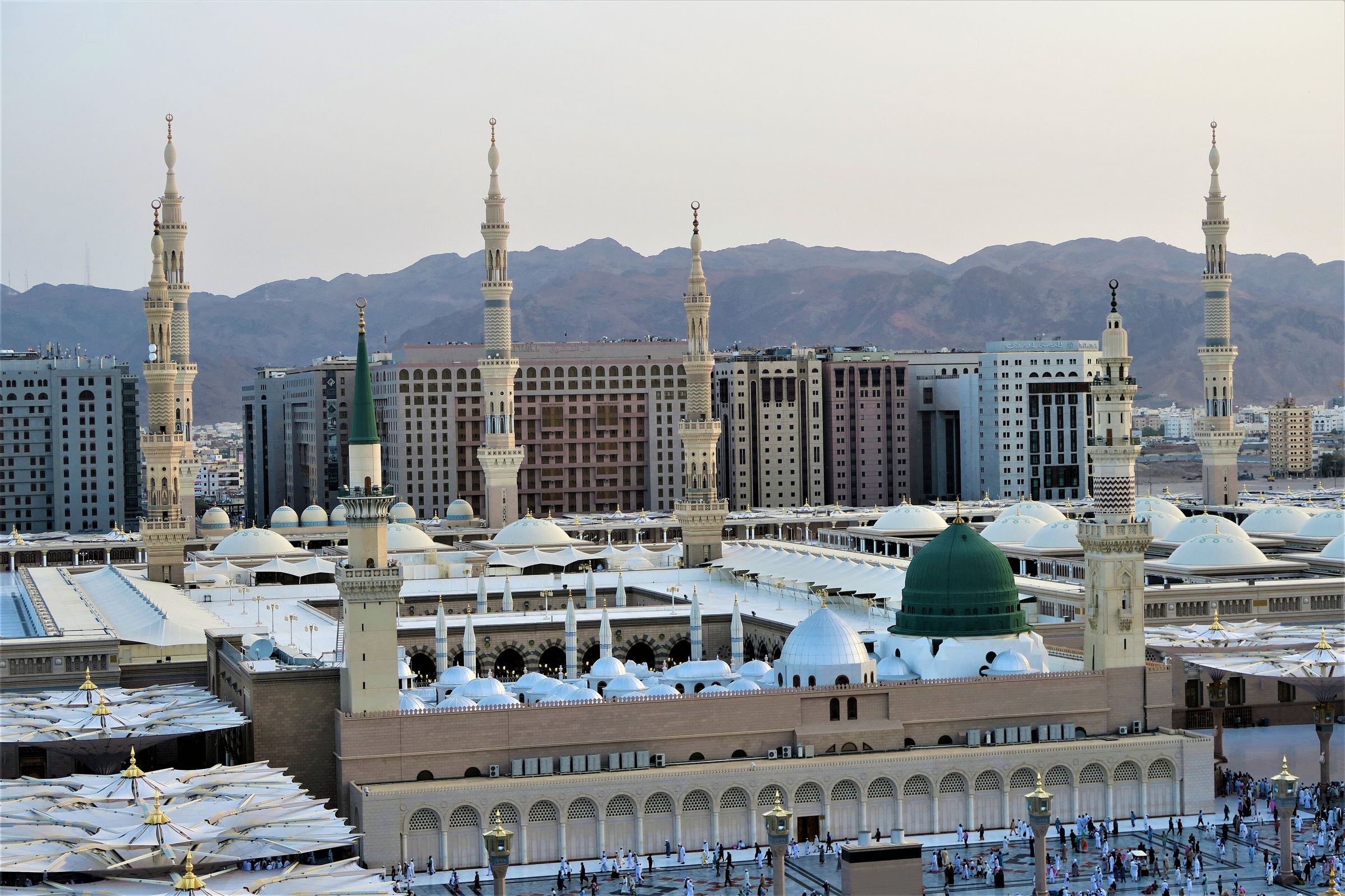 Al-Masjid an-Nabawi from above: the Green Dome, white domes of the prayer hall and minarets, with the mountains of Madinah behind